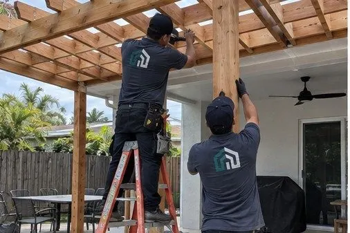 Contractors assembling a cedar pergola over a backyard patio